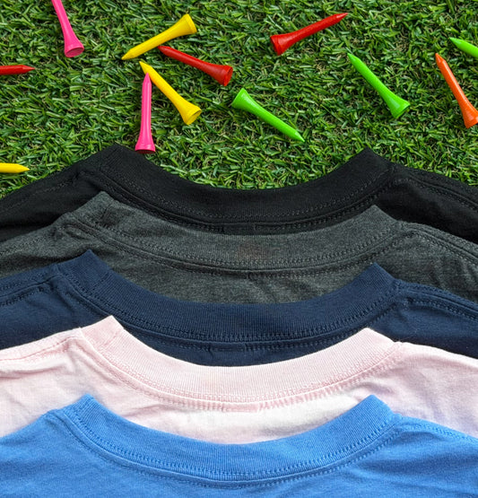 Close-up of the necklines of Royal-Tee long sleeve golf shirts in heather Columbia blue, pink, navy, heather charcoal, and black, displayed on green turf with colorful golf tees scattered around.