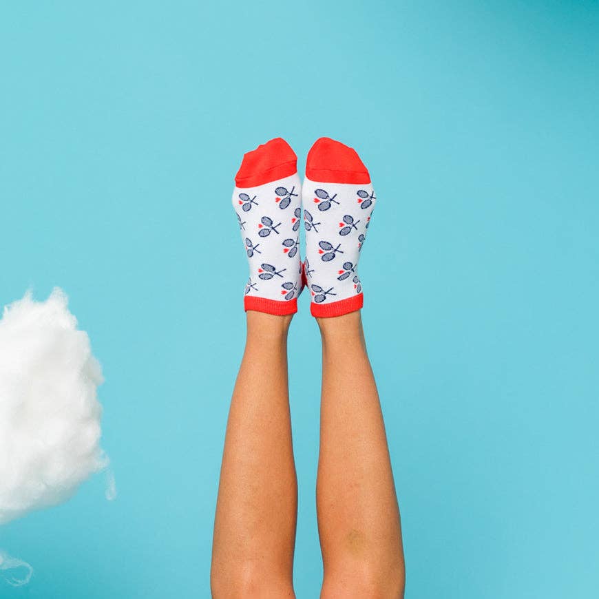 Legs raised against a blue background wearing white ankle socks with red cuffs and tennis racket pattern