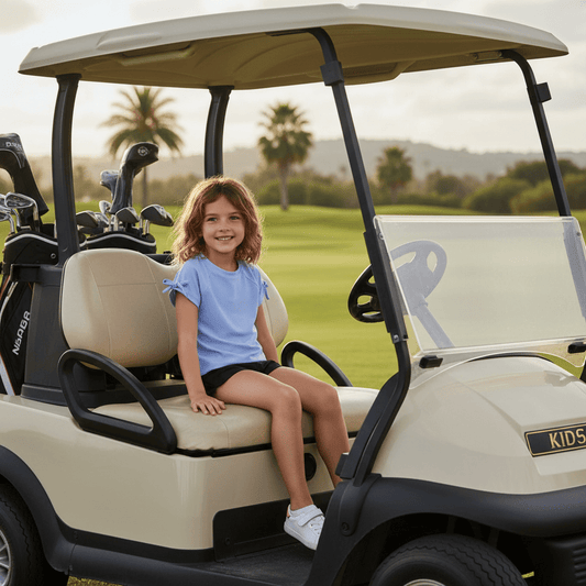 Girl wearing girls performance raglan with bow detail shirt sitting in a golf cart on a sunny golf course