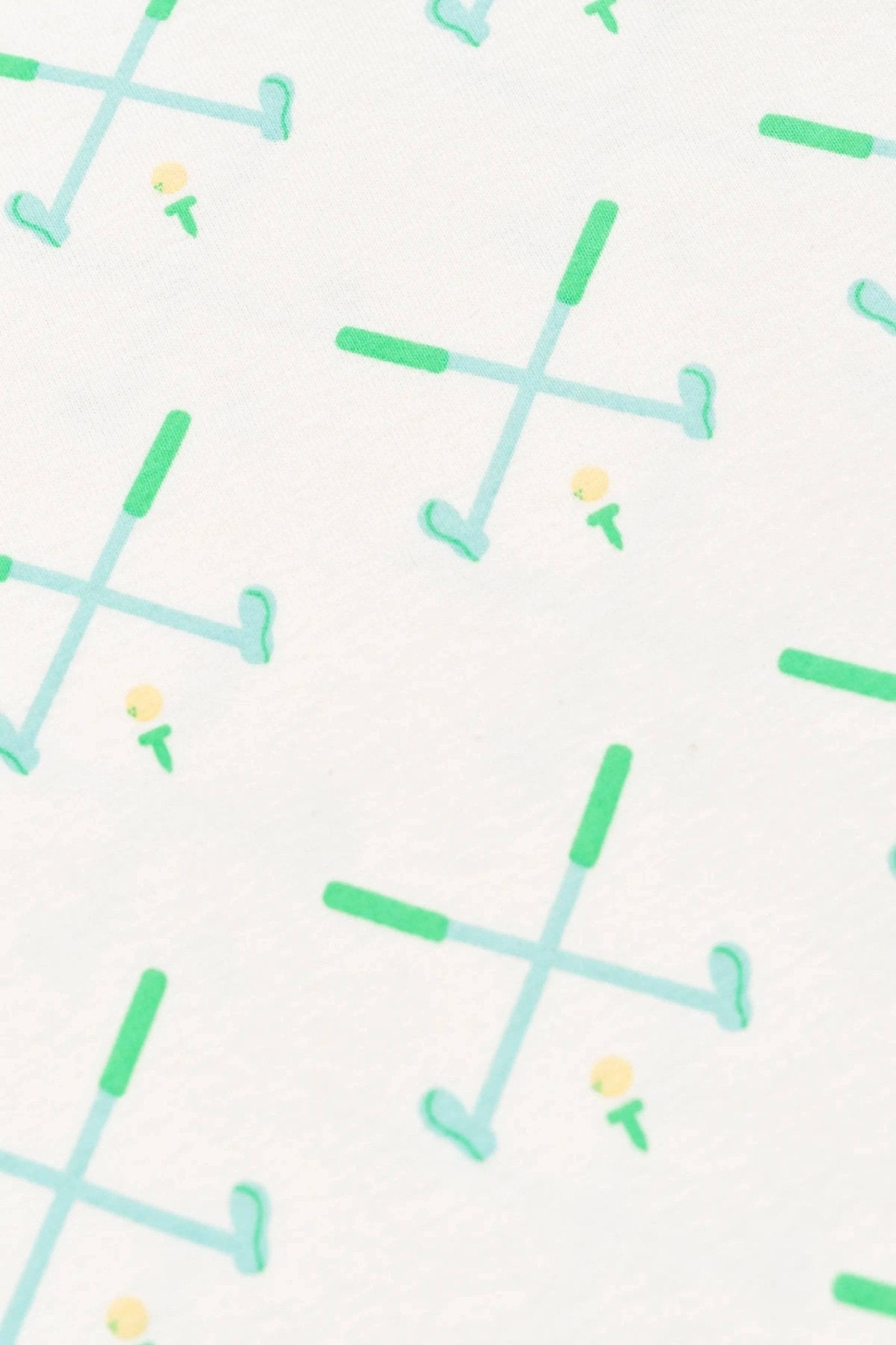 Close up shot of the pattern on the white golf sleeper. Blue golf clubs with green handle crossed over each other. Yellow golf ball on a green tee in between the crossed clubs.