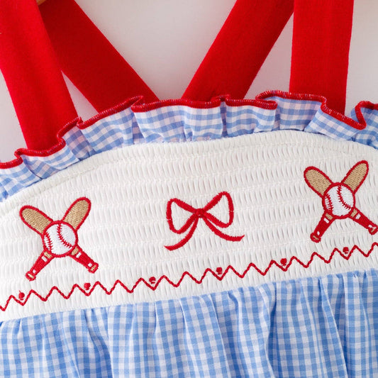 Close-up of smocked baseball embroidery and red straps on baby girls romper