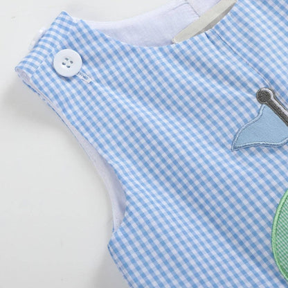 Close-up of blue gingham baby shortall shoulder with white button and soft cotton fabric