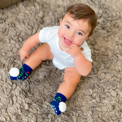 Baby wearing rattle socks with golf pattern. Navy with different color pin flags and golf balls. Soft golf ball rattle on the toes.