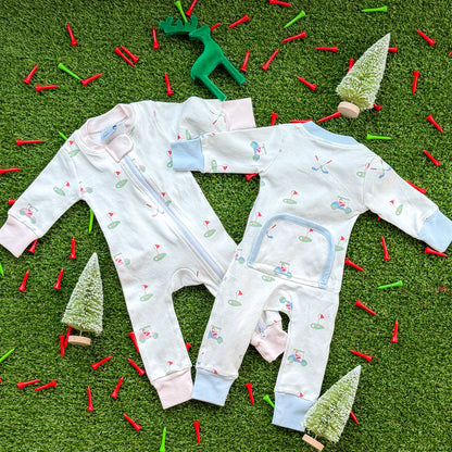 Set of Aster and Ace holiday golf baby onesies in pink and blue trims with Santa golf cart and golf green pattern, photographed flat lay with Christmas décor.