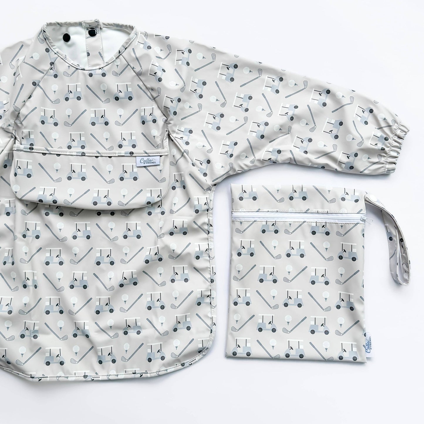 Long sleeved grey bib with golf cart pattern. Shown on a white background with wet/dry bag