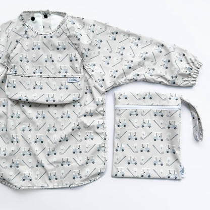 Long sleeved grey bib with golf cart pattern. Shown on a white background with wet/dry bag