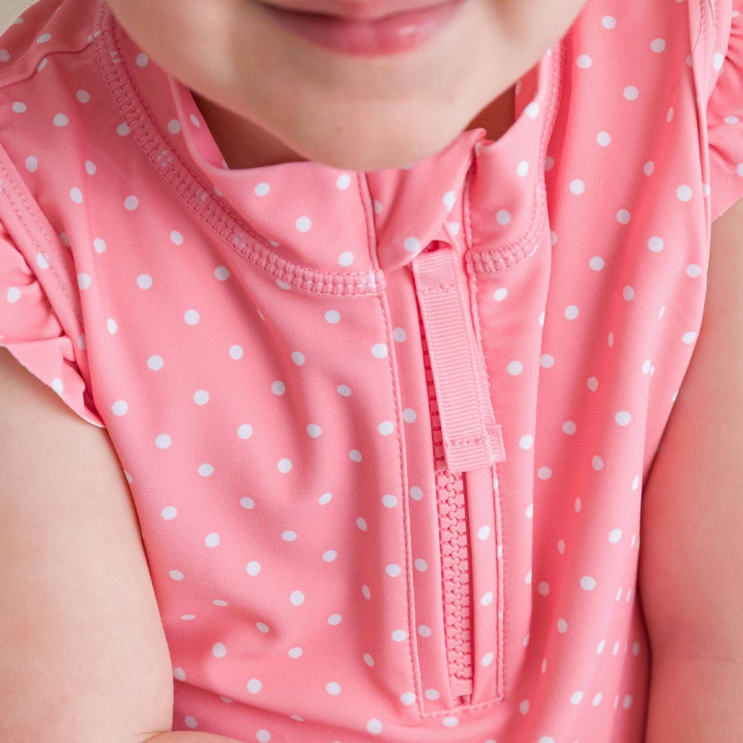 Close-up of pink girls top with white polka dots and quarter-zip neckline detail