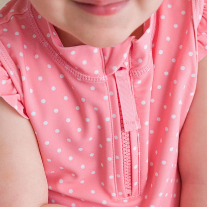 Close-up of pink girls top with white polka dots and quarter-zip neckline detail