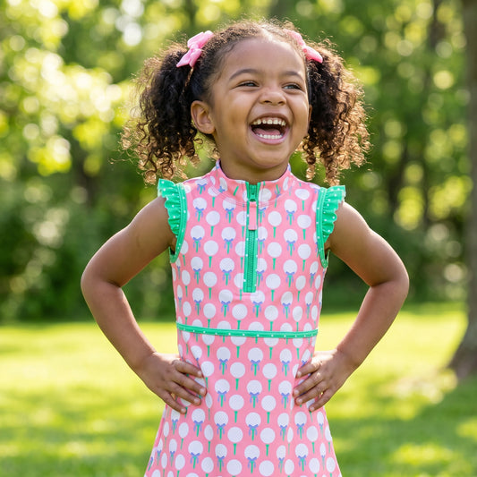 Young girl in a pink dress with green trim and golf ball accents.