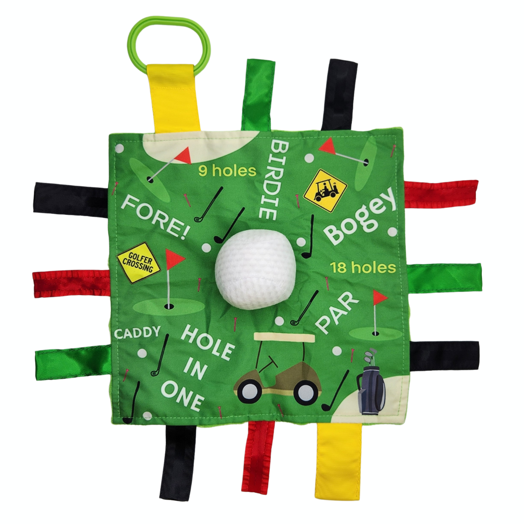 Golf themed sensory lovey for babies. Green background with multi-colored ribbons coming out on the sides. Golf words written on it and a squishy golf ball in the middle. 