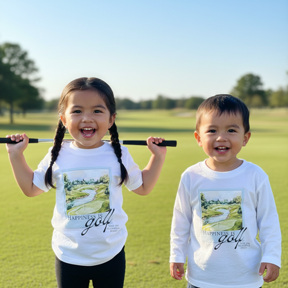 Two young children wearing Aster and Ace “Happiness Is Golf” shirts, smiling on a golf course with one holding a golf club.