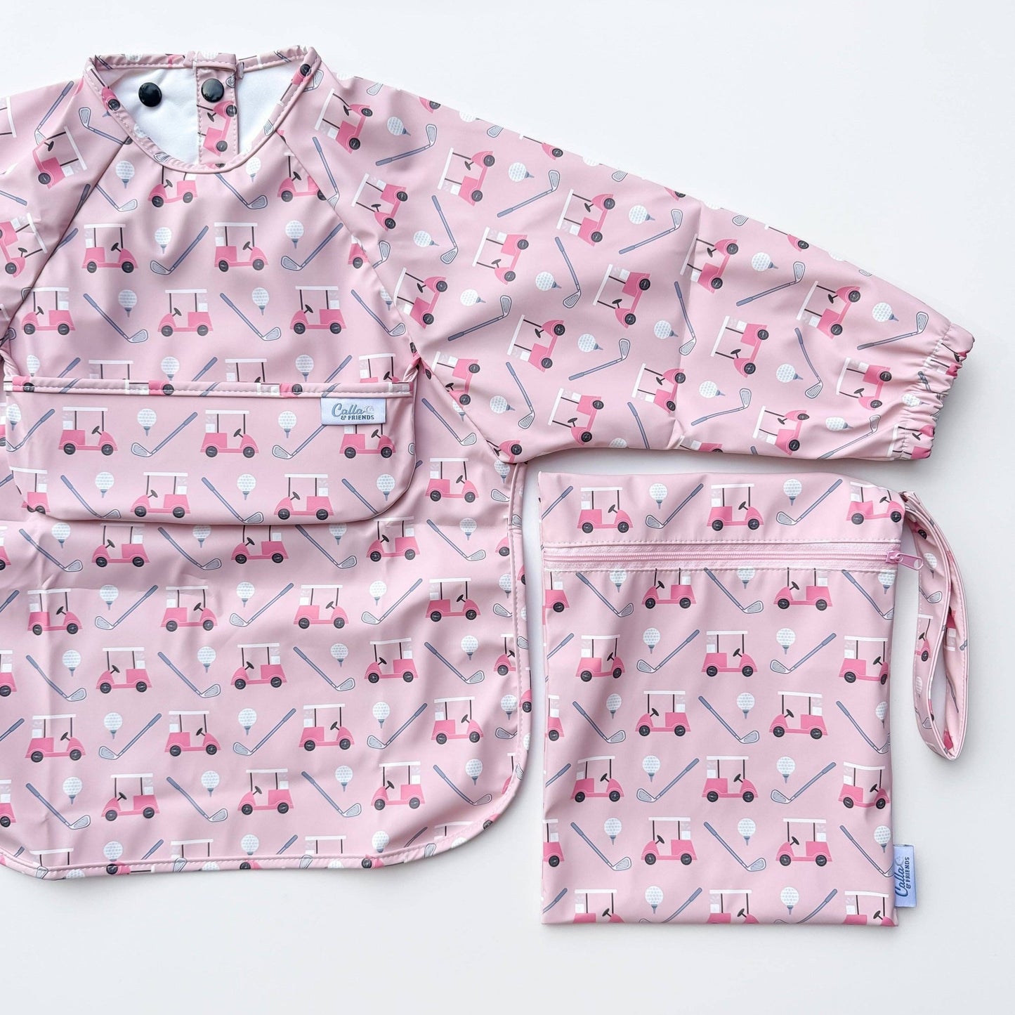 Long sleeved pink bib with golf cart pattern. Shown on a white background with wet/dry bag