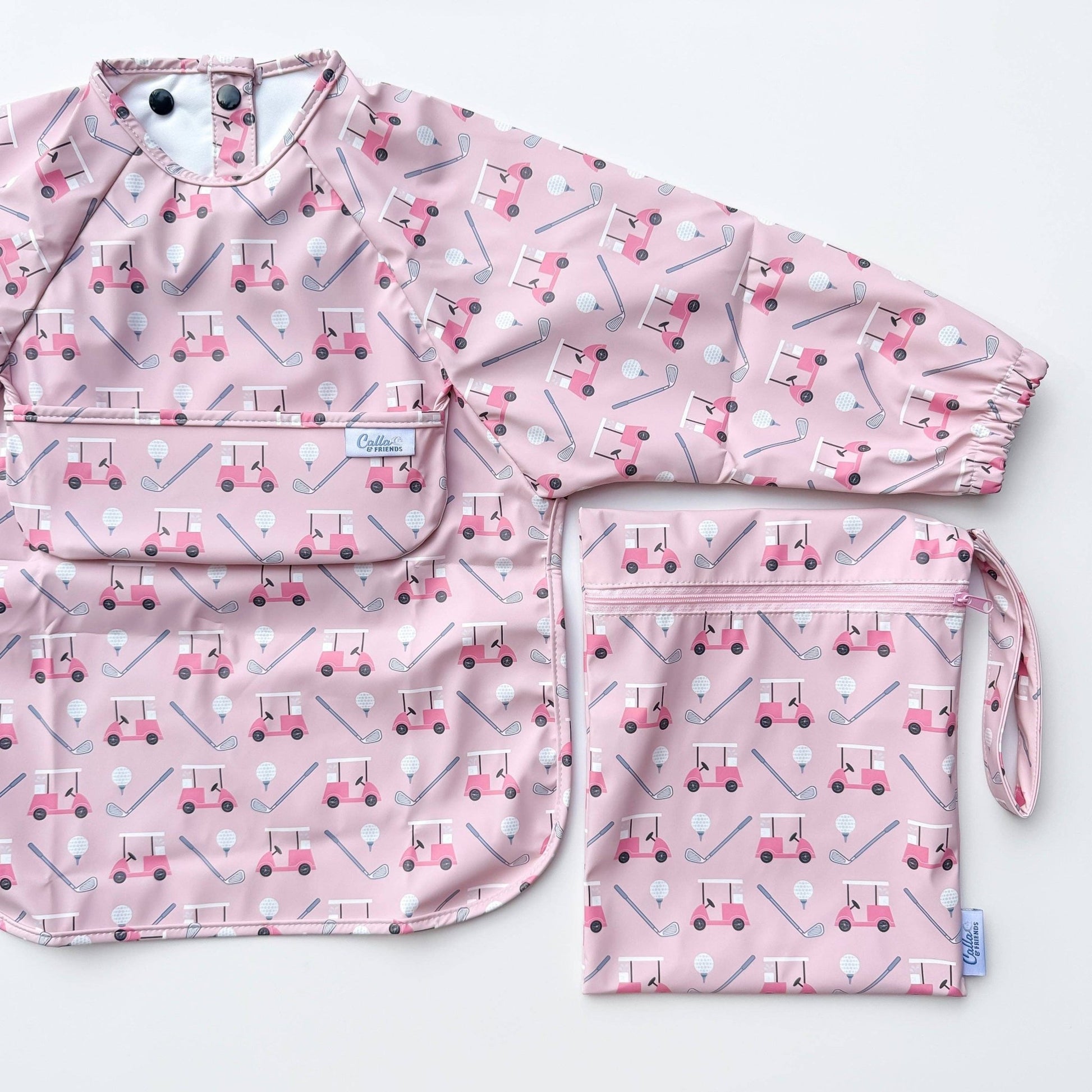 Long sleeved pink bib with golf cart pattern. Shown on a white background with wet/dry bag