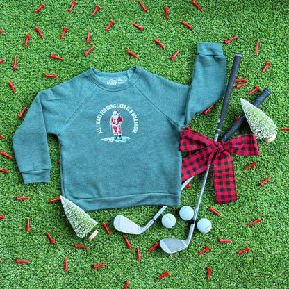 Heather forest green kids’ Christmas sweatshirt featuring a Santa golfing graphic with “All I Want for Christmas Is a Hole in One,” styled on turf with golf tees, golf clubs, golf balls, and holiday décor.