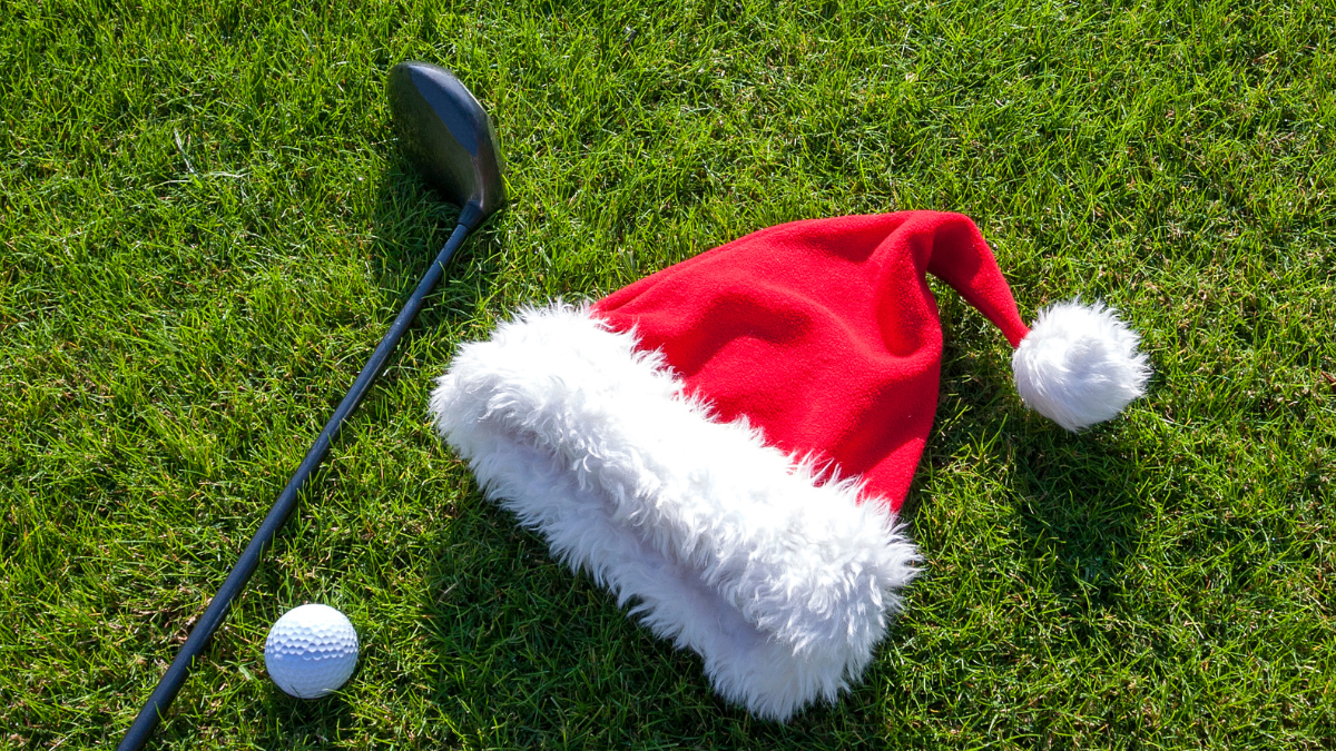 Santa hat, golf club, and golf ball on a grassy surface