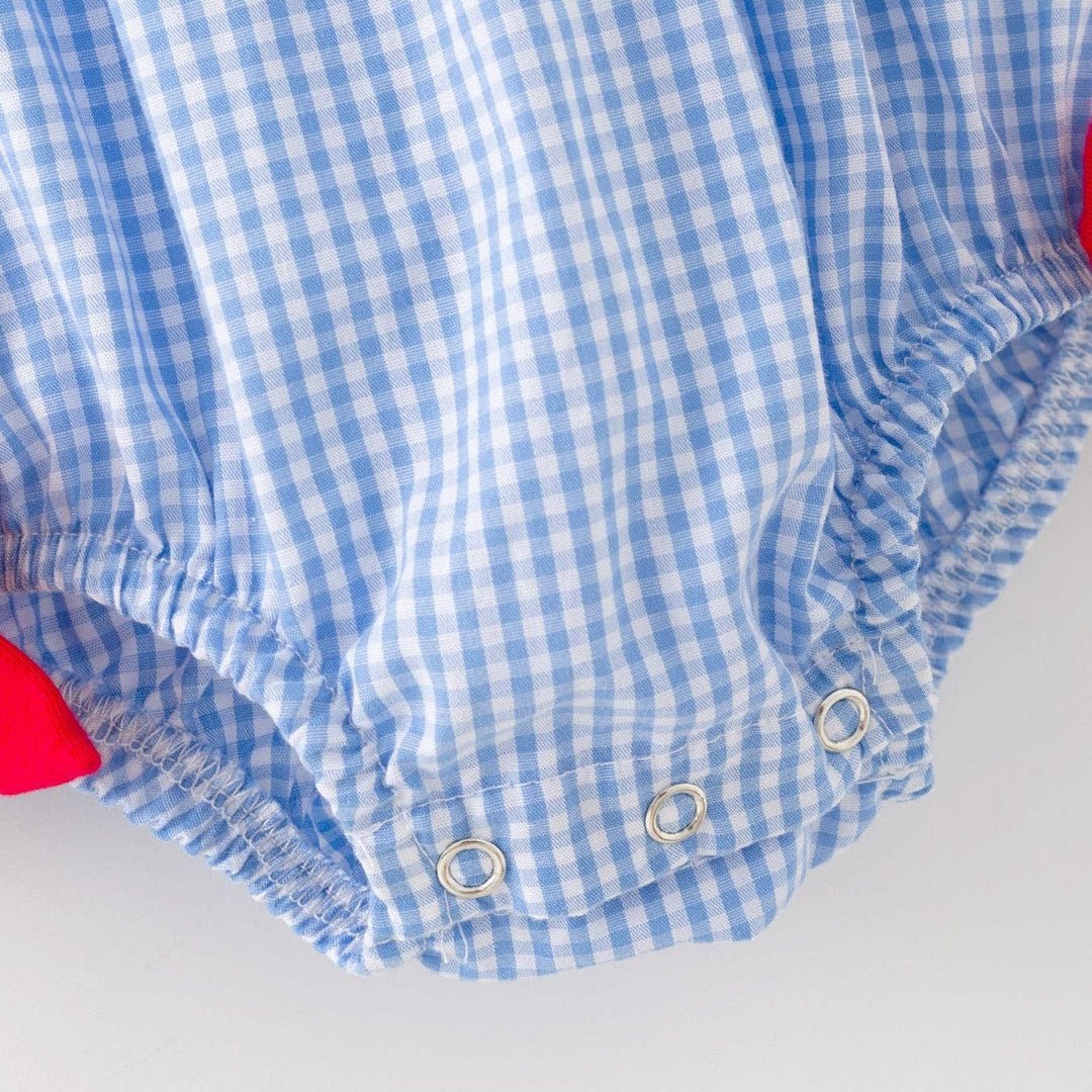 Close-up of snap closure and blue gingham fabric on baby baseball romper