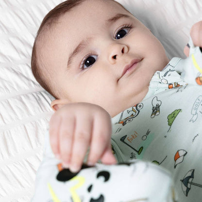 Baby lying on a white blanket wearing golf print onesie