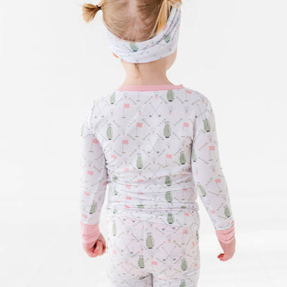 back of golf pajamas with pink trim and pin flags and green golf bags 