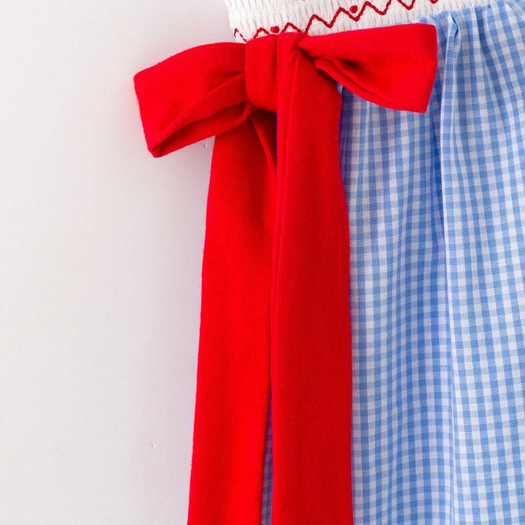 Side detail of red bow accent on blue plaid toddler baseball dress