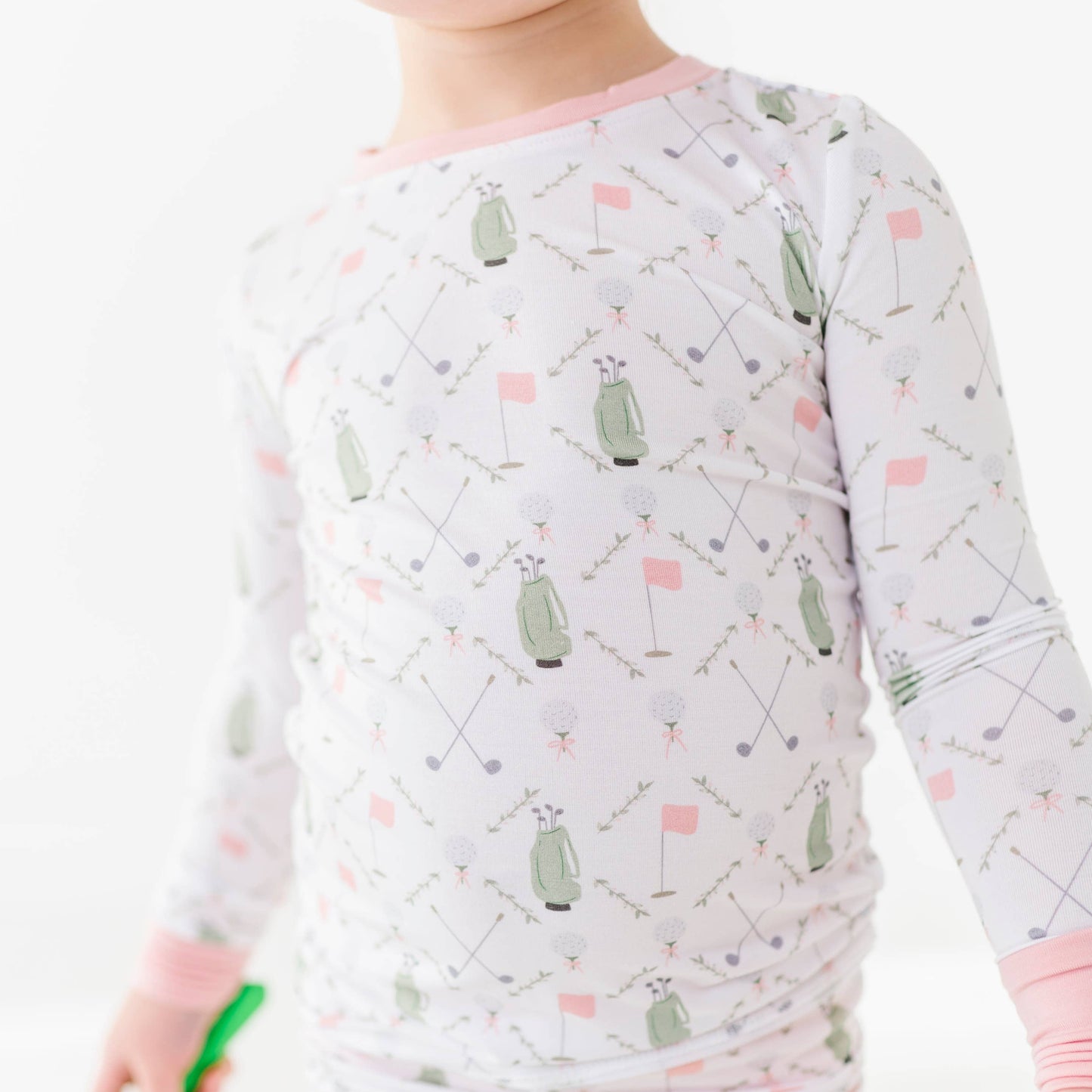 detail shot of girls golf pajamas white with pink pin flags and green golf bags