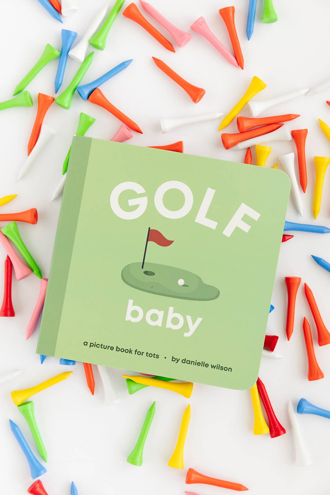 Golf-themed children's book surrounded by colorful golf tees on a white background