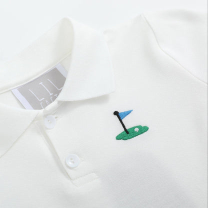 Close-up of embroidered golf pin detail on white kids polo shirt