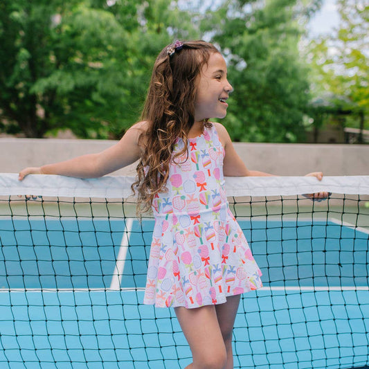 Young girl in activewear dress with colorful pickleball paddles and bow pattern. 