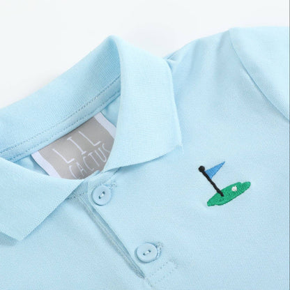 Close-up of embroidered golf pin detail on light blue kids polo shirt