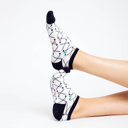 Low-cut athletic socks with navy heel and toe accents, white body with crossed golf club pattern, worn on feet posed heel-to-toe against a white background