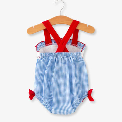 Back view of baby girls blue plaid baseball smocked romper with red cross straps and bow accents