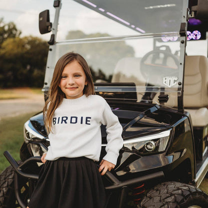 girl wearing golf clothing white sweater with navy birdie across front