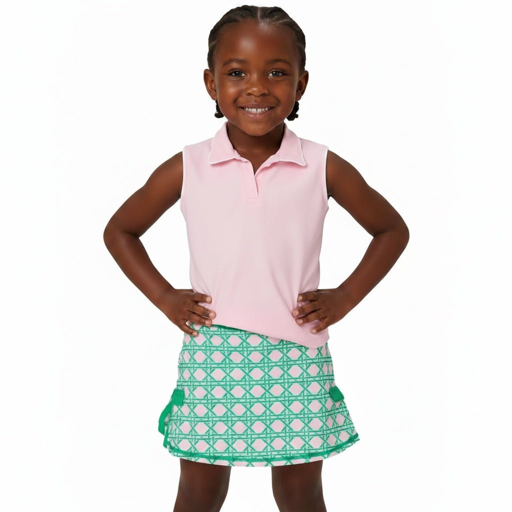 Girl posing in athletic outfit with pink sleeveless polo and pink and green skort with bow detail on the sides
