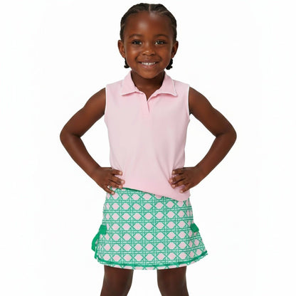 Girl posing in athletic outfit with pink sleeveless polo and pink and green skort with bow detail on the sides