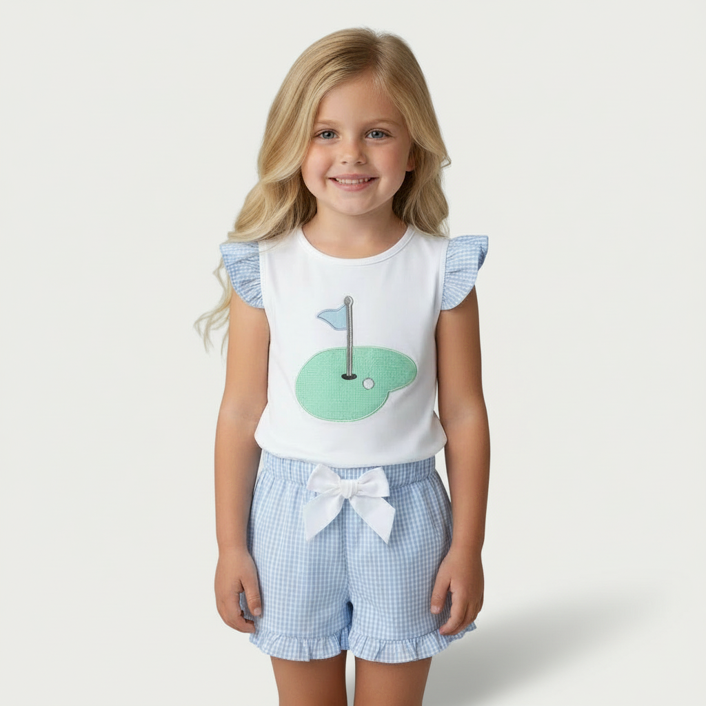 Toddler girl wearing a light blue gingham golf hole ruffle tee and shorts set, featuring a golf green appliqué and ruffle sleeves.