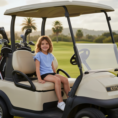 Girl wearing girls performance raglan with bow detail shirt sitting in a golf cart on a sunny golf course