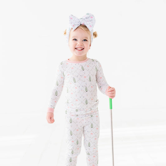 girl wearing girls pink and white golf pajamas with green golf bags