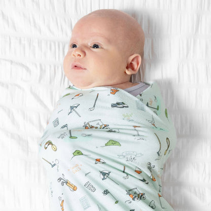 Baby wrapped in light blue swaddle blanket with golf cartoons 