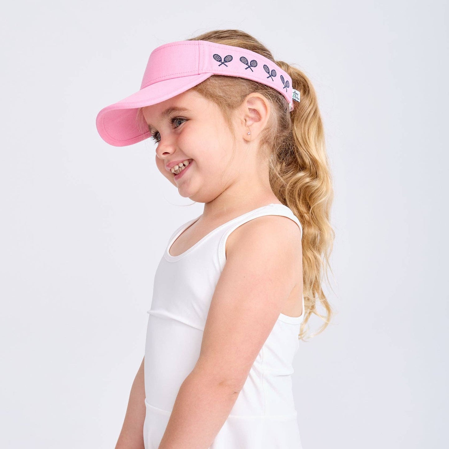 Side profile of young girl wearing pink embroidered canvas visor with ponytail
