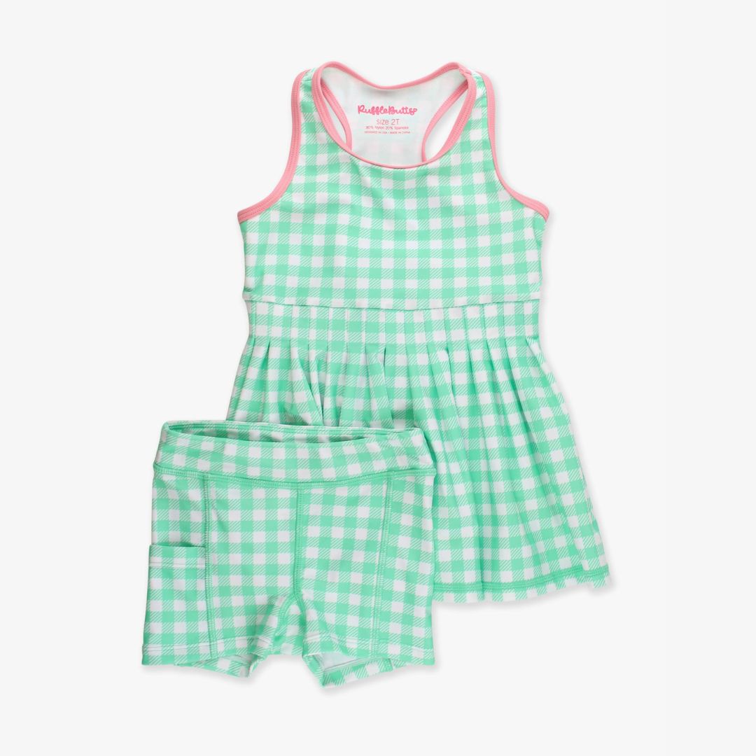 Green gingham pleated active dress with matching bike shorts featuring side pocket, laid flat on white background.