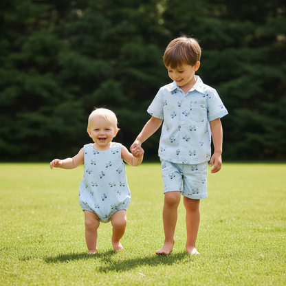 Toddler boys in matching blue golf outfits from the Tatum Collection walking hand in hand on a sunny golf course