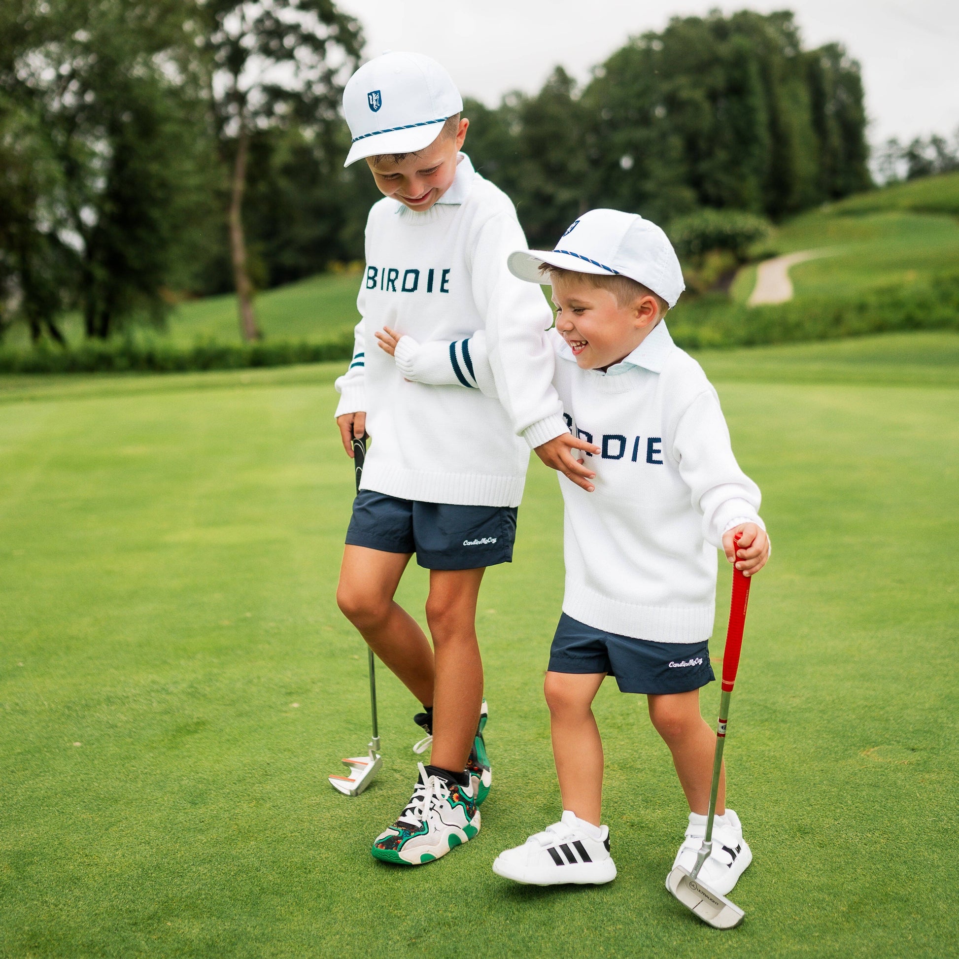 Boy and toddler wearing golf sweater with birdie across chest