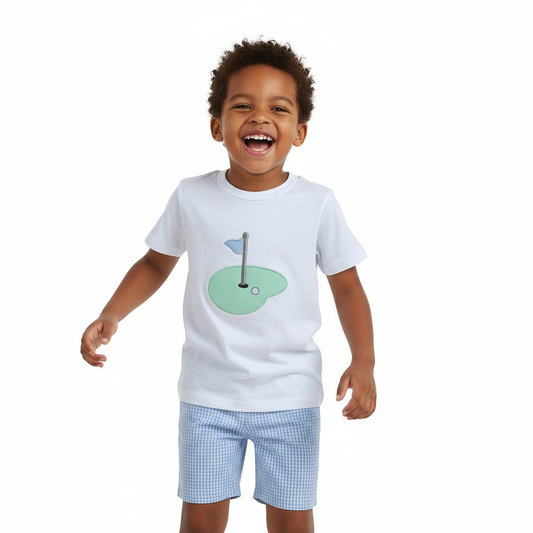 Toddler boy wearing golf hole shirt and blue gingham shorts set, smiling in studio