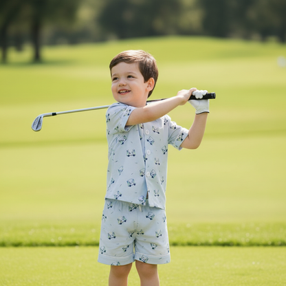 Toddler boy playing golf on a green while wearing the Tatum Boy Golf Short Set, featuring a light blue golf cart print shirt and coordinating shorts, designed for comfortable active play.
